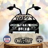 Black time machine car birthday cake topper with raised gull-wing doors, Happy lettering, personalized age 10th, and the name Luke.