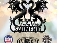Black wedding cake topper with two winged dragons forming a heart-shaped opening, Mr and Mrs lettering, and the personalized surname SAUMENIG.