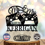 Black wedding cake topper with two game controllers, Mr and Mrs script, the date 06.07.26, and the personalized surname KERRIGAN.
