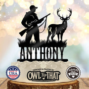 Black personalized cake topper featuring a hunter holding a scoped rifle beside an antlered buck, with grass details above the name.