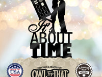 Black It’s About Time wedding cake topper featuring an embracing couple beside a tilted police call box time machine above stacked lettering.