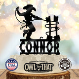 Black personalized CONNOR birthday cake topper featuring a little cowboy in a hat and boots holding a lasso beside a rustic fence.