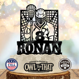Black lacrosse birthday cake topper featuring a helmeted player holding a stick in front of a goal, personalized with the name Ronan and age 8.