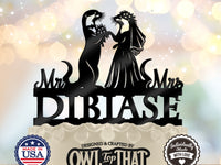Black otter bride and groom wedding cake topper with a veil, floral details, Mr and Mrs lettering, and the personalized surname DIBIASE.