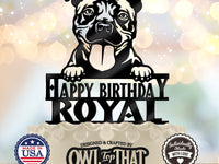 Black pit bull birthday cake topper with folded ears, tongue out, paws above Happy Birthday lettering, and the personalized name ROYAL.
