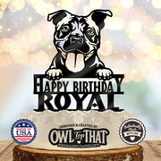 Black pit bull birthday cake topper with folded ears, tongue out, paws above Happy Birthday lettering, and the personalized name ROYAL.